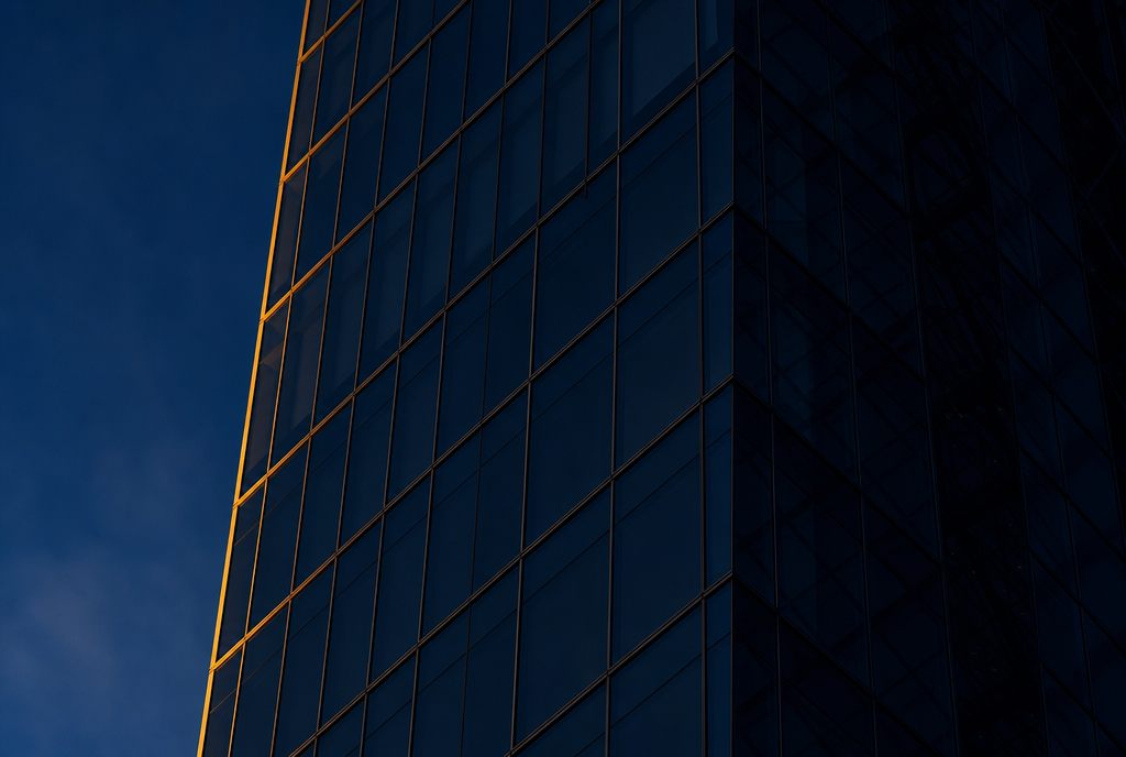 Modern glass office facade at dusk with golden light edge